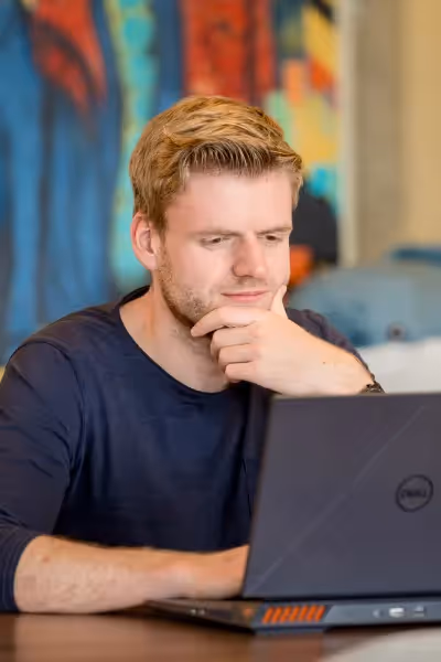 Athos van Kralingen sitting in front of laptop and contemplating
