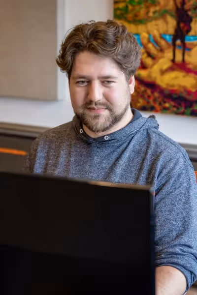 Darius Bouma sitting in front of computer screens, working